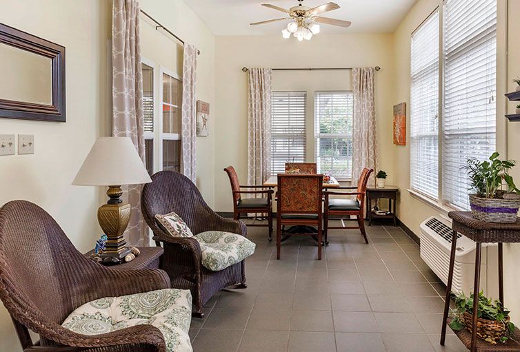 A cozy living room with a dining table, chairs, and ample natural light.
