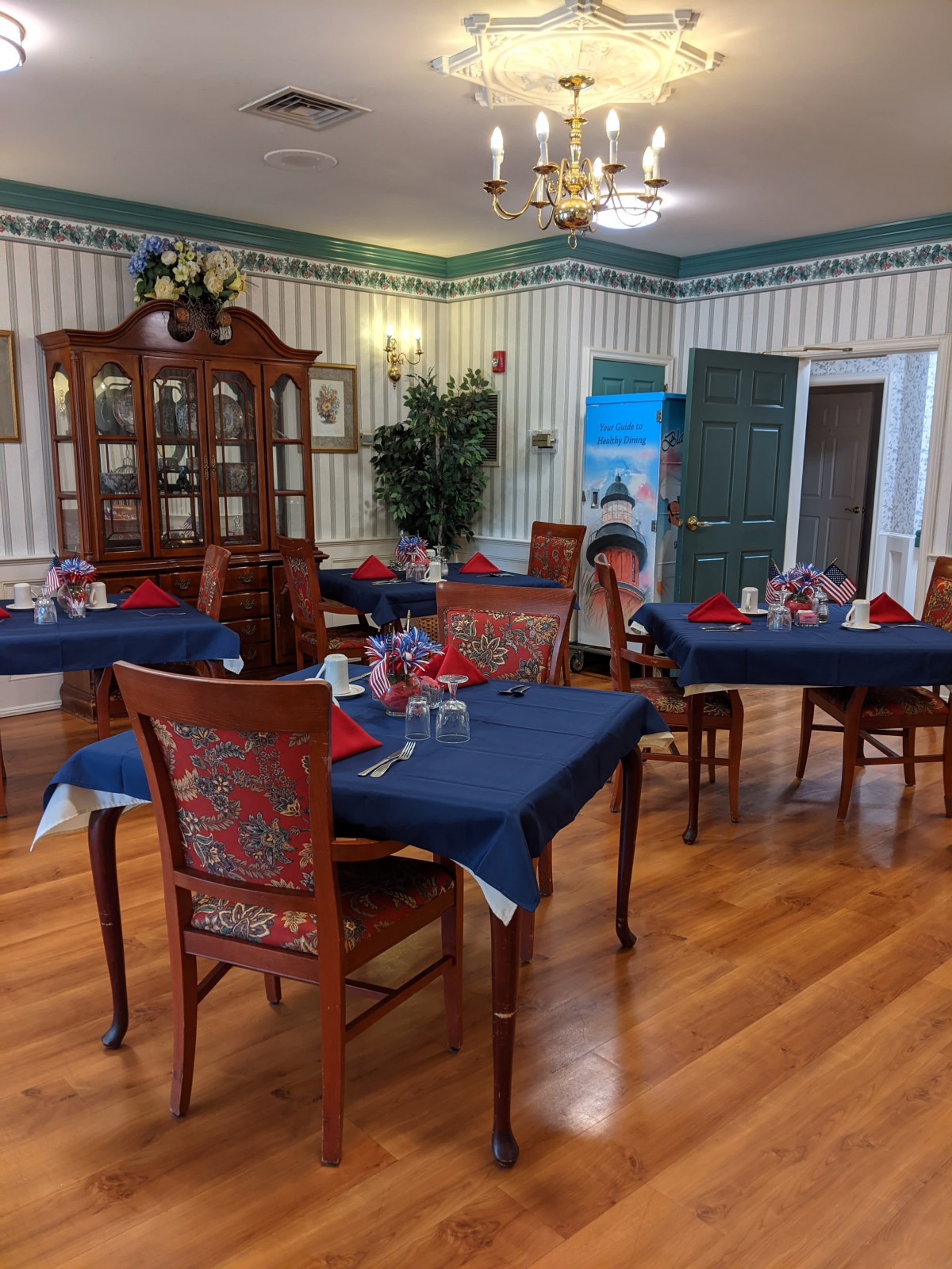 A beautifully decorated dining room with wooden flooring and tables set with blue tablecloths.