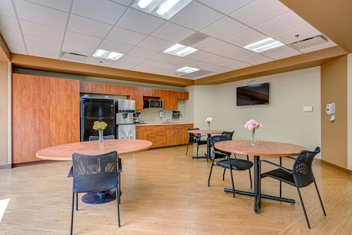A modern kitchen and dining area featuring wooden cabinetry, round tables, and a cozy atmosphere.