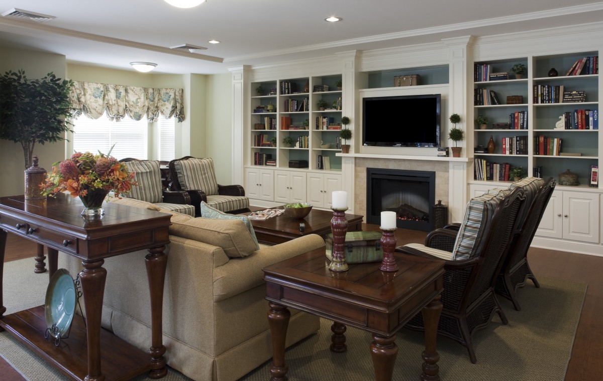 A well-furnished living room featuring a cozy seating area, built-in bookshelves, and a fireplace with a television above.