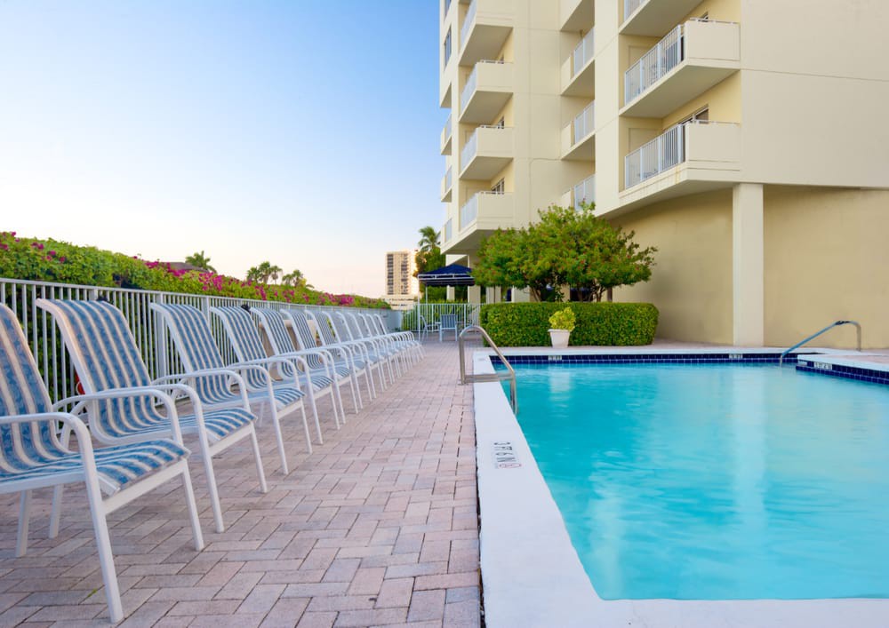 An inviting swimming pool located alongside a hotel, with lounge chairs arranged neatly along the poolside.