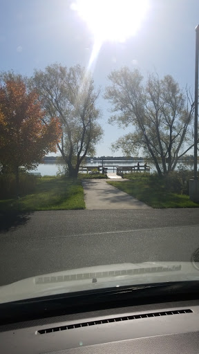 A serene view of a lake with a wooden pier surrounded by trees.