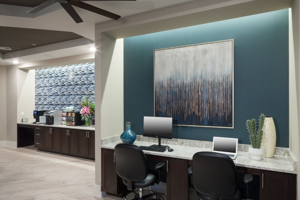 A modern office workspace featuring computers and abstract artwork on the wall.