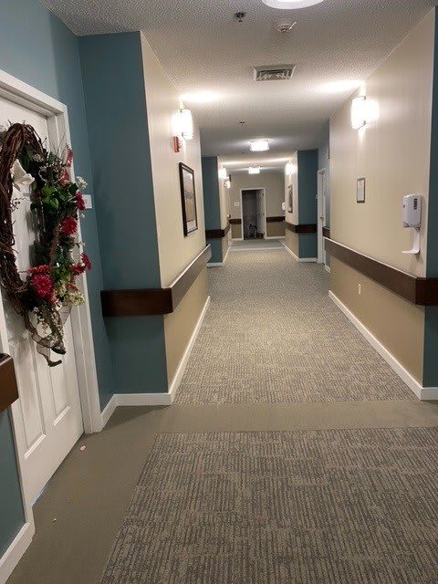 A decorated hallway with a wreath on the door and carpeted flooring.