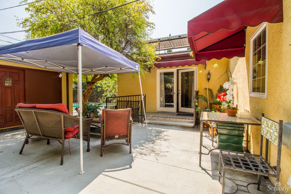 A cozy backyard patio with outdoor seating and canopy on a sunny day.