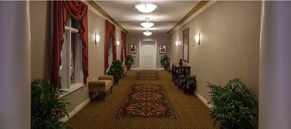 A well-lit hallway with patterned carpet, decorative wall art, and comfortable seating.