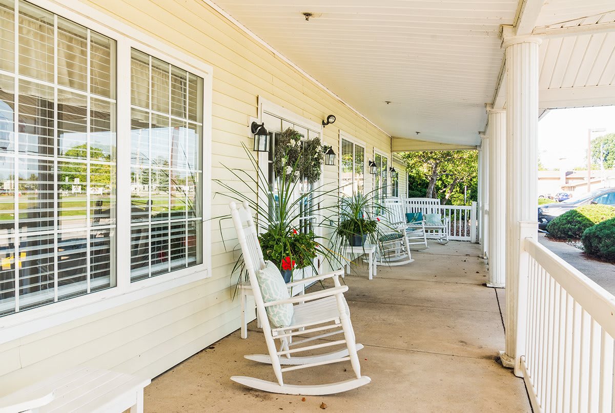 A cozy porch with rocking chairs and plants on a sunny day.