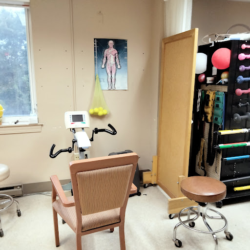 A therapy room equipped with exercise bikes, therapy tools, and a human anatomy poster.