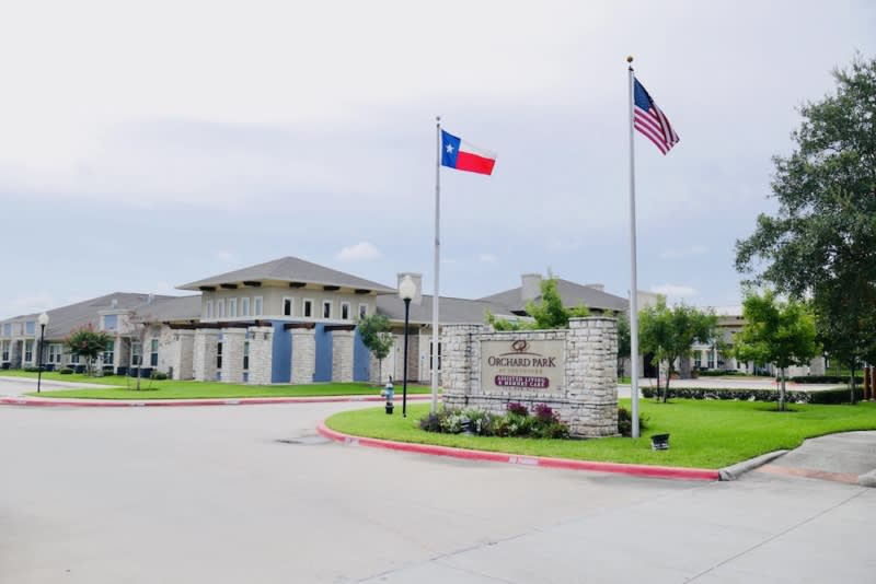 Entrance to an apartment complex with the Texas and American flags displayed.