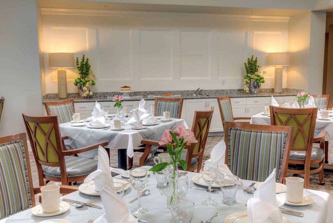 An elegantly set dining room with neatly arranged tables and floral decorations.