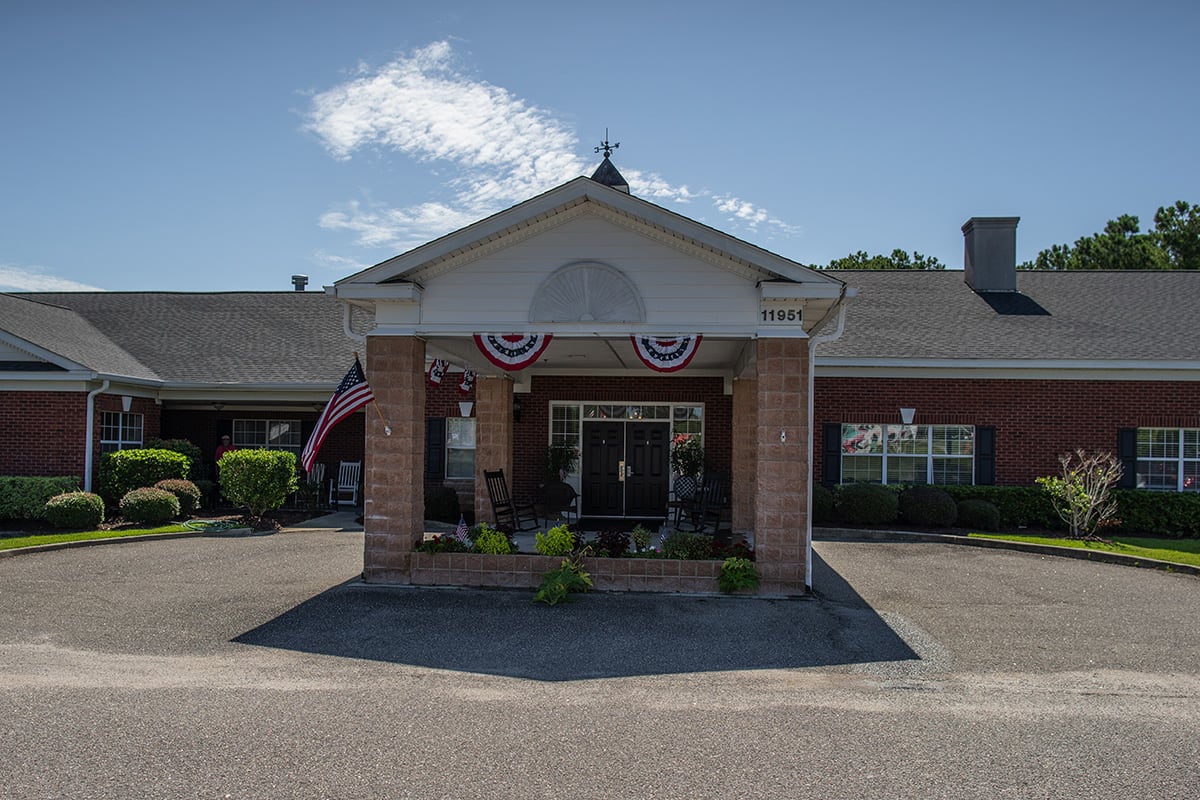 A building entrance decorated with American flags and patriotic bunting on a sunny day.