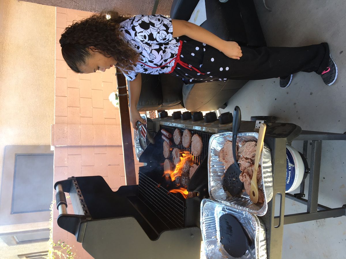 A person grilling hamburgers on an outdoor barbecue.
