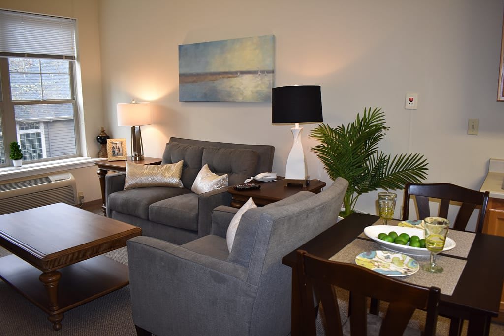 A cozy living room with plush gray sofas, complemented by ambient lighting and tasteful artwork.