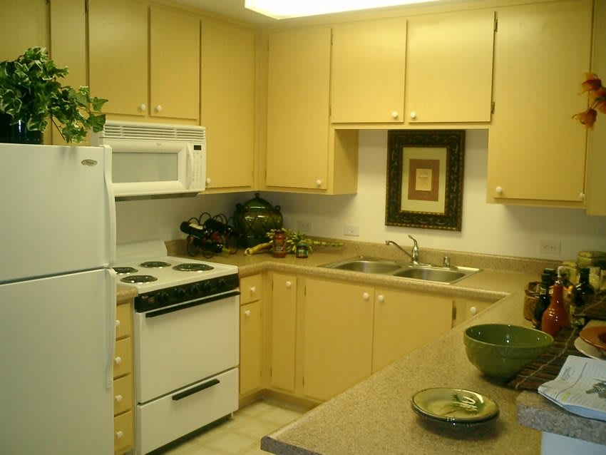 A cozy kitchen with yellow cabinets, a stove, and a microwave.