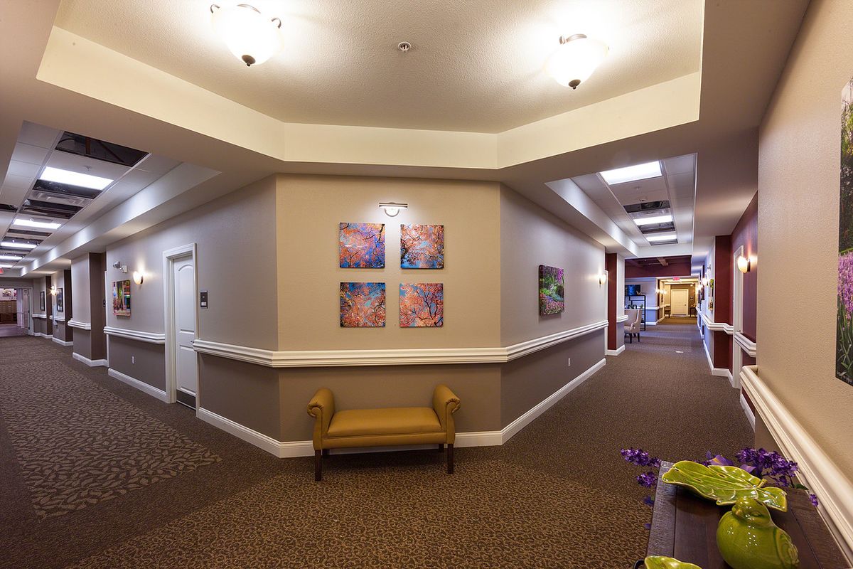 A well-lit hallway featuring colorful artwork and a small bench along the wall.