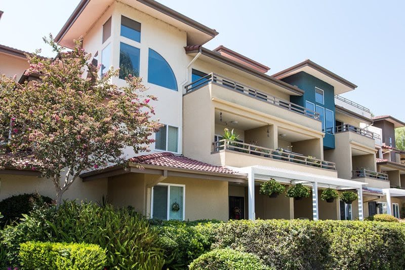 A modern residential apartment building with balconies and landscaped surroundings.