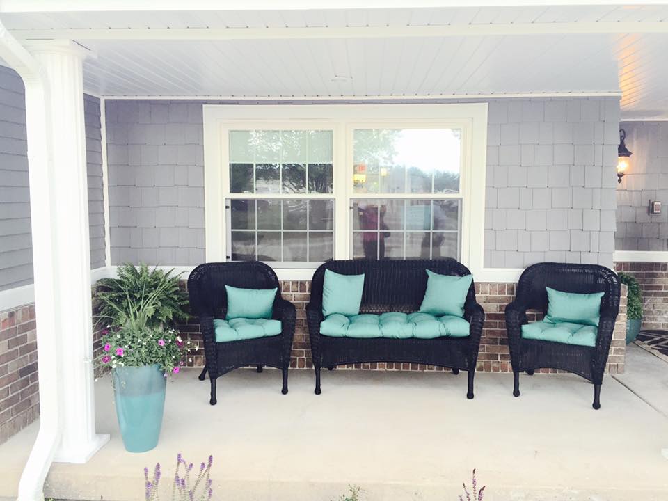 A cozy porch with black chairs and teal cushions, perfect for relaxing outdoors.