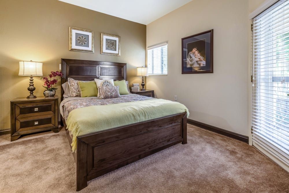 A cozy bedroom with a wooden bed frame, decorative pillows, and elegant wall art.
