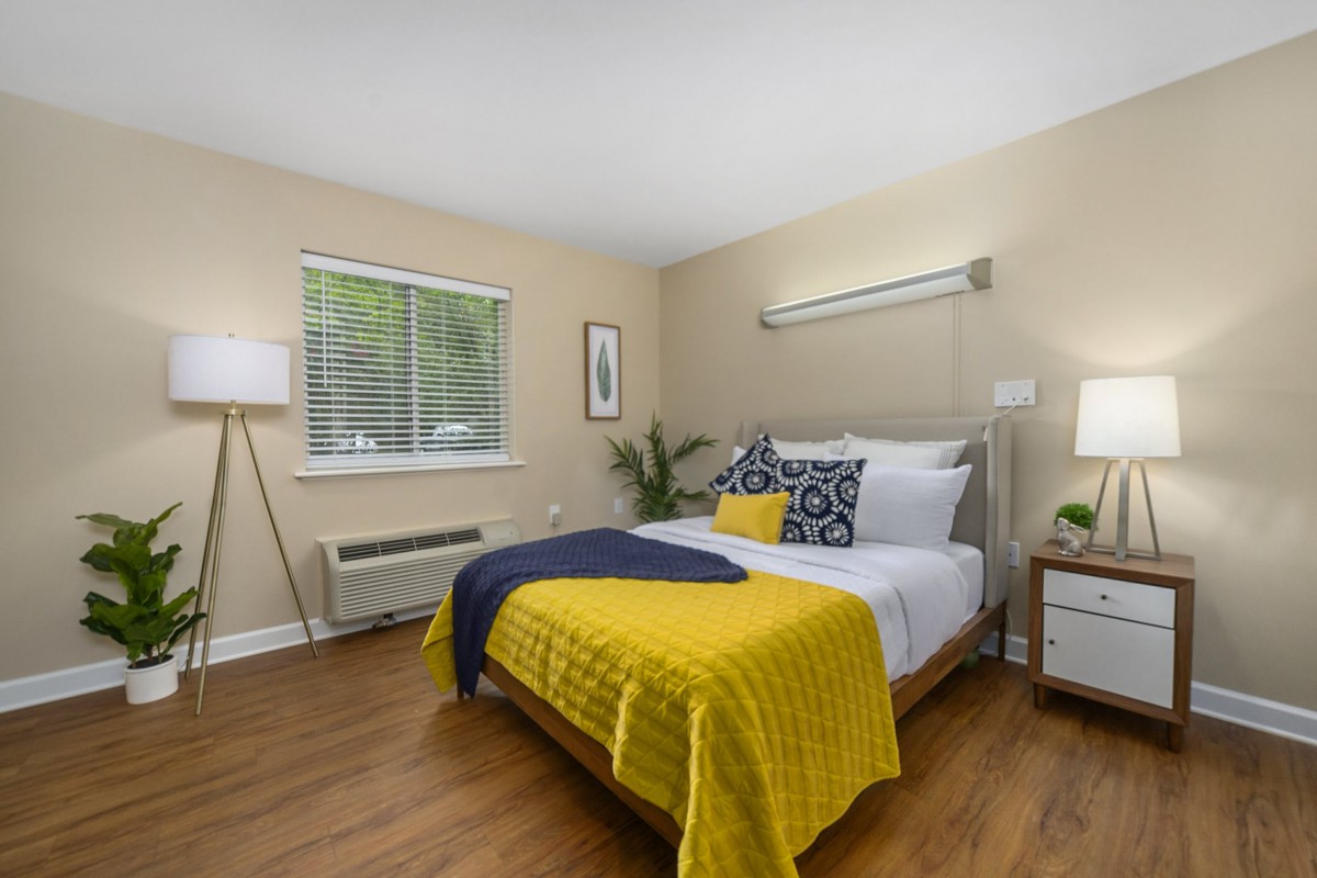 A cozy bedroom featuring a modern decor with a bed, pillows, and a bright yellow blanket.
