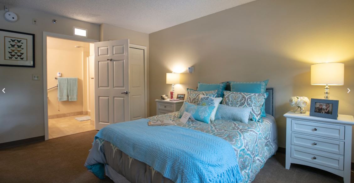 A cozy bedroom with blue bedding and a softly lit lamp on the nightstand.