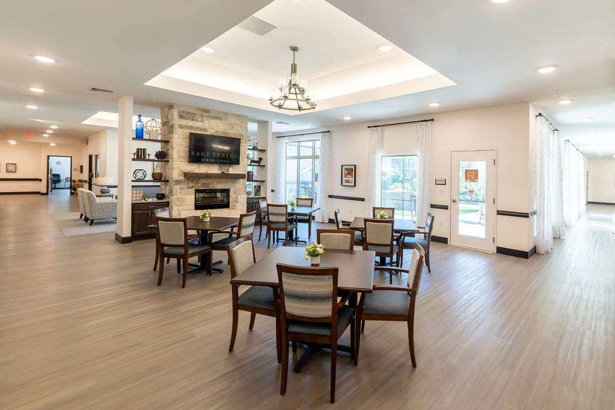 A modern dining area with a cozy fireplace, chandelier, and elegant tables and chairs.