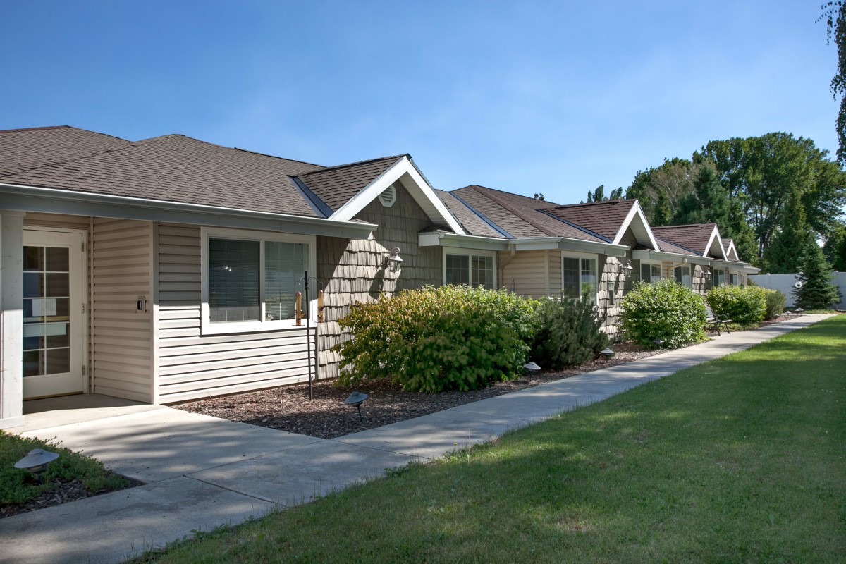 A row of suburban homes with well-maintained landscaping and a sidewalk.