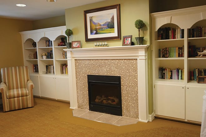 A cozy living room with a central fireplace, framed by white shelves filled with books and decor.
