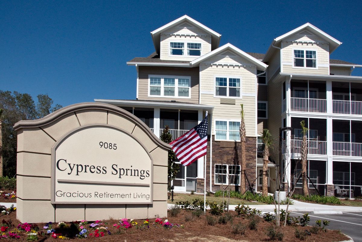 Cypress Springs Gracious Retirement Living building with an American flag.