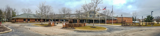A modern building surrounded by trees under a cloudy sky.