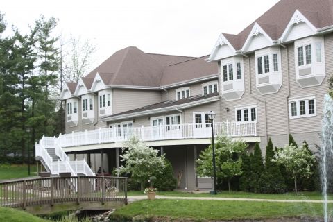 A large residential house with multiple windows and balconies surrounded by trees.