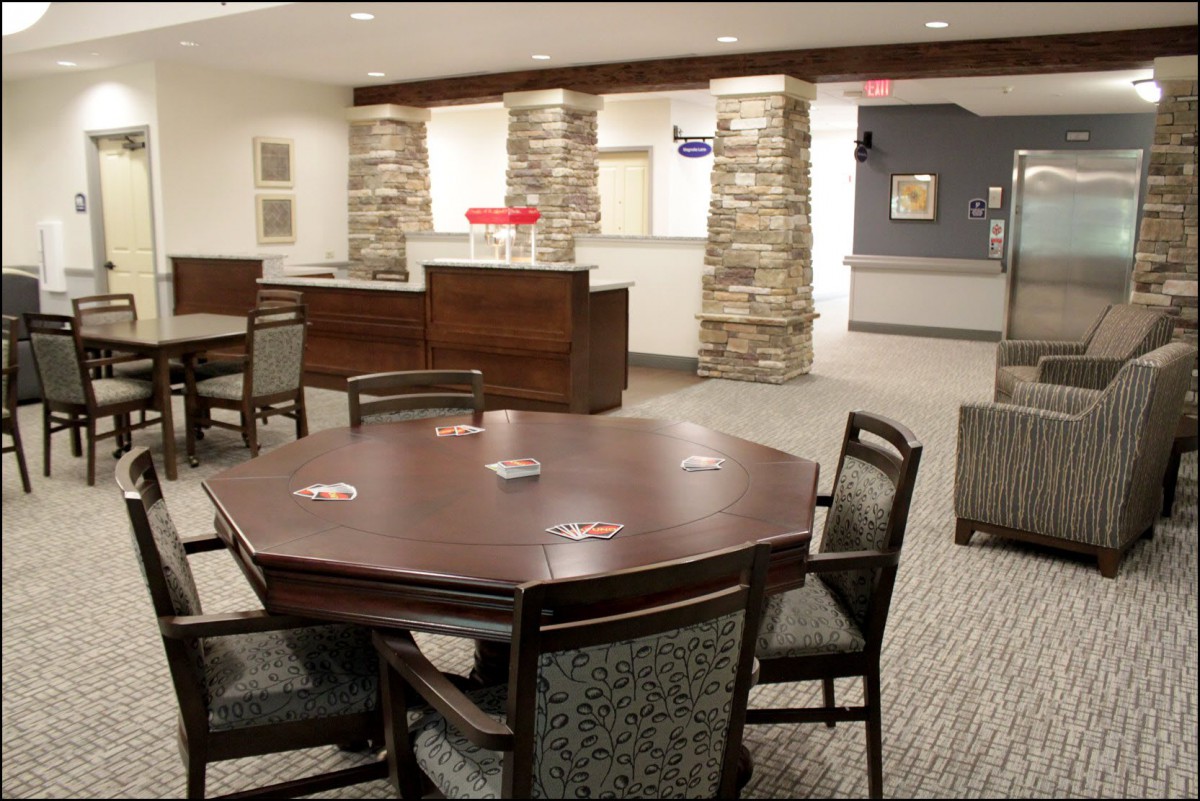 A cozy lobby area with a table and chairs, featuring stone pillars and warm lighting.