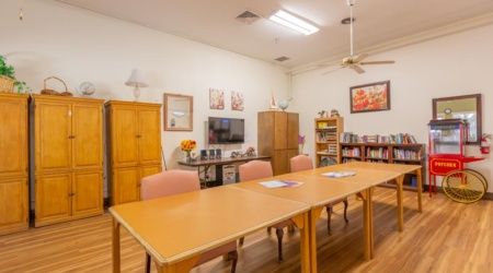 A cozy conference room equipped with a long table, chairs, television, and bookshelf.