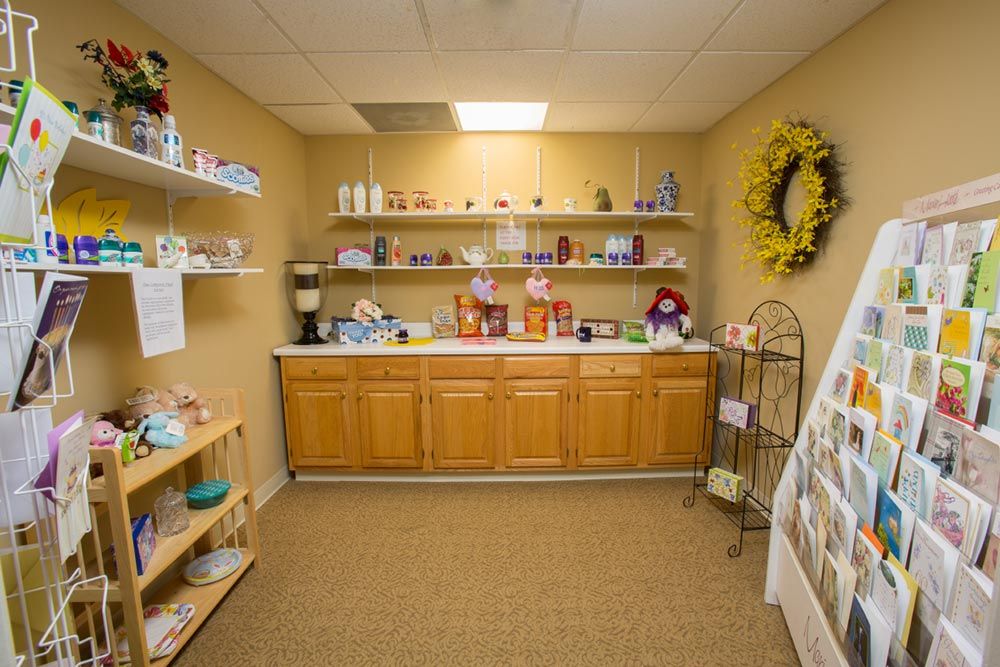 Interior of a small gift shop with shelves displaying various products and a decorative wreath on the wall.