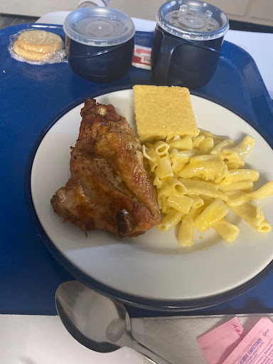A hearty meal featuring roasted chicken, pasta, and cornbread served on a tray.