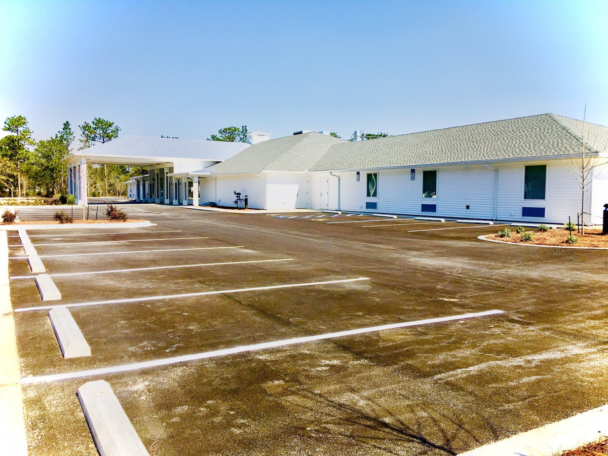 A view of a building with an adjoining parking lot under a clear sky.