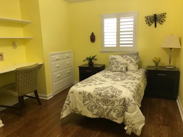 Cozy bedroom with yellow walls and a floral-patterned single bed.