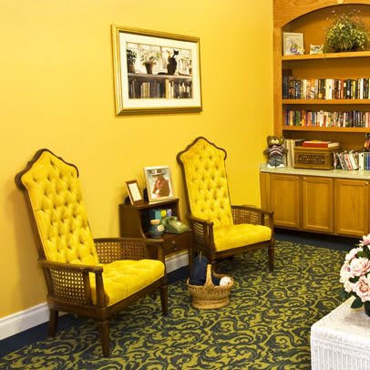 A cozy room featuring yellow upholstered chairs, a bookshelf, and decorative elements.
