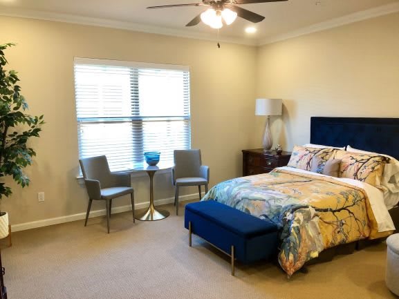 A cozy bedroom with a bed, chairs, and a small table by the window.