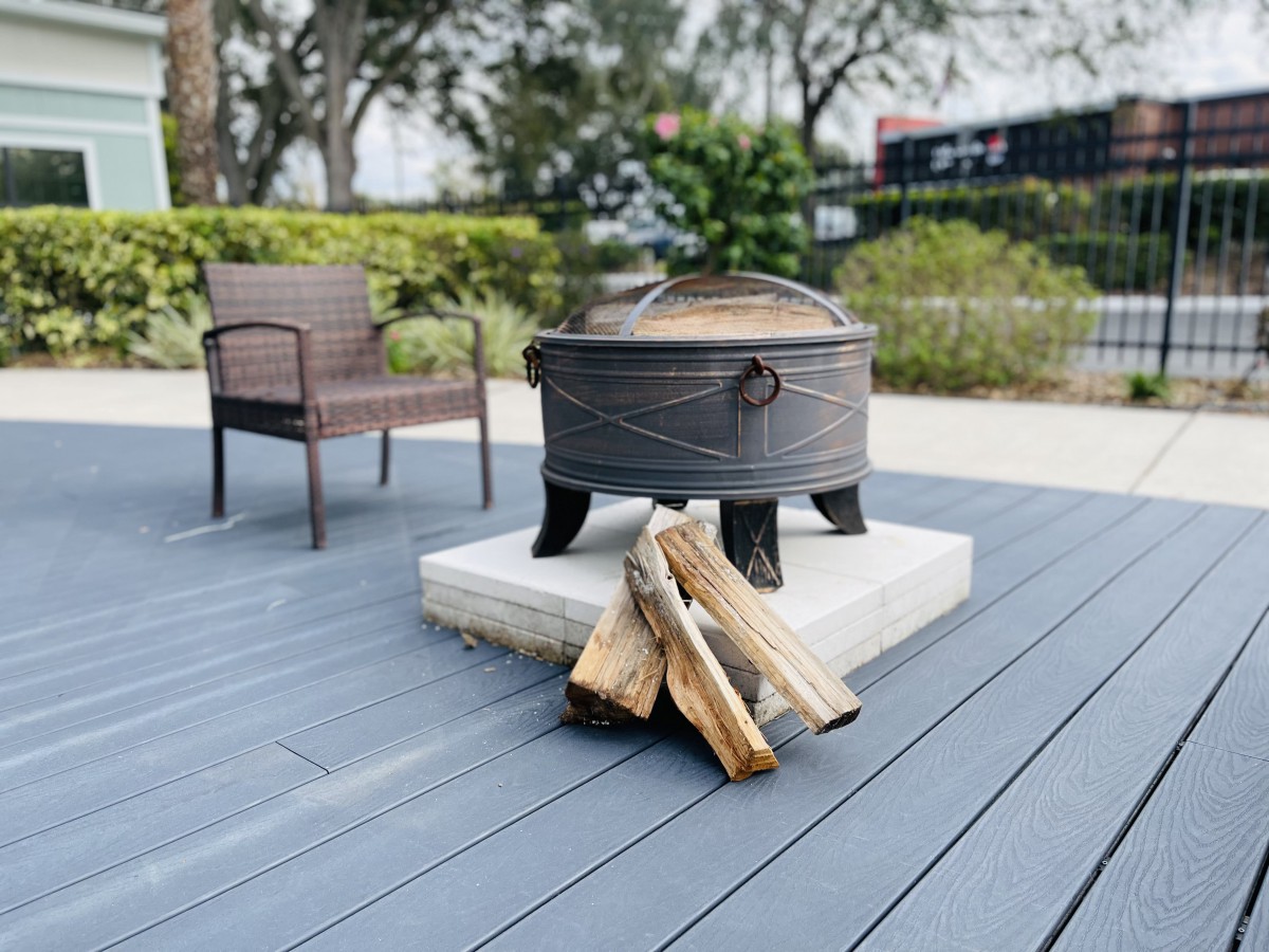 A cozy outdoor setup featuring a fire pit with stacked wood logs, perfect for relaxation on the patio.