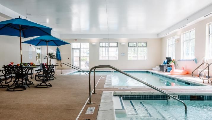 A serene indoor swimming pool area with lounge chairs and umbrellas.