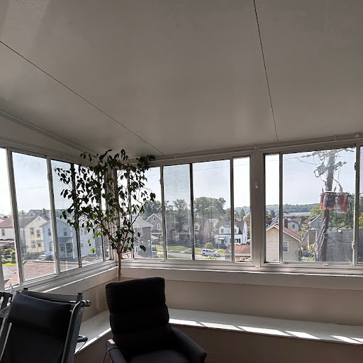 A bright sunroom with large windows offering a view of the city.