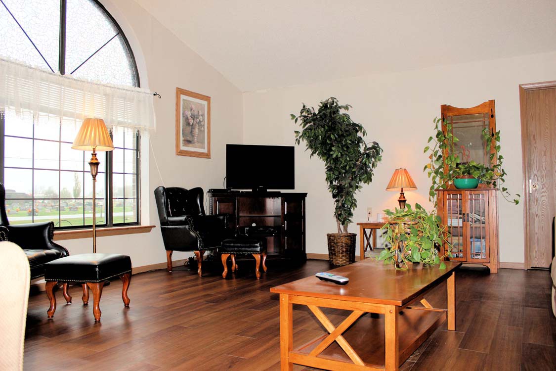 A cozy living room with wooden furniture, indoor plants, and a television.