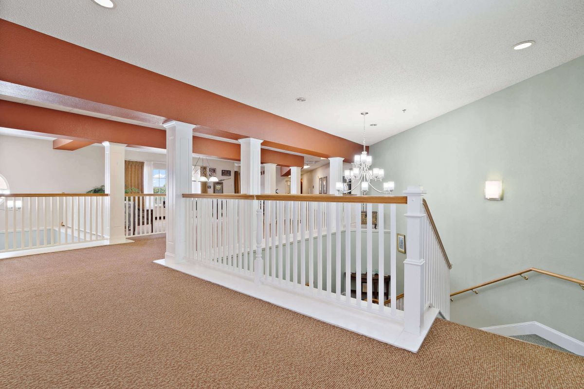 Spacious interior area featuring a carpeted floor and a white staircase banister.