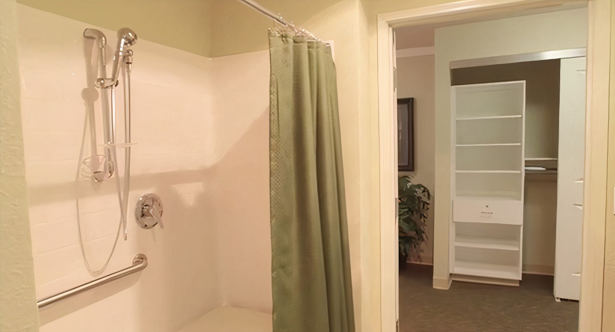 A view of a bathroom featuring a shower with a green curtain.