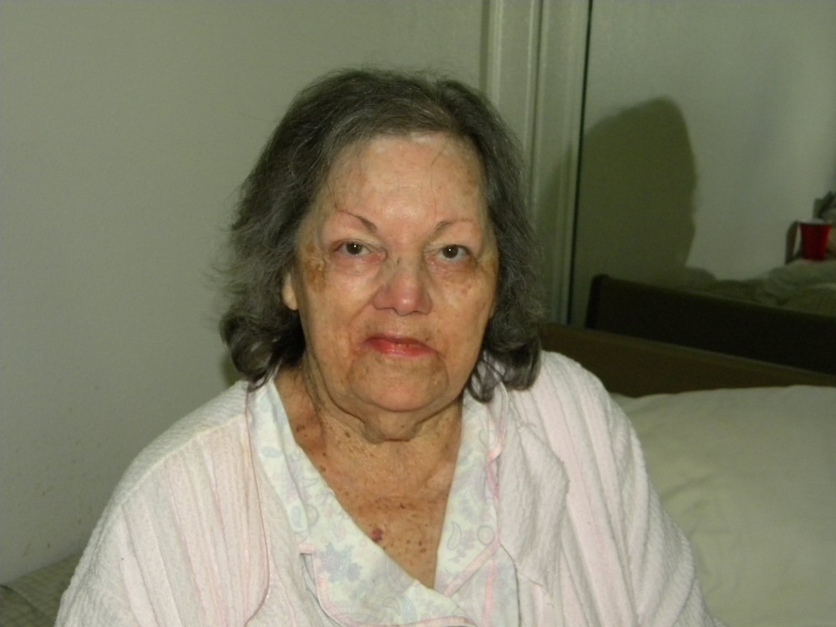 An elderly woman sitting indoors in casual clothing.