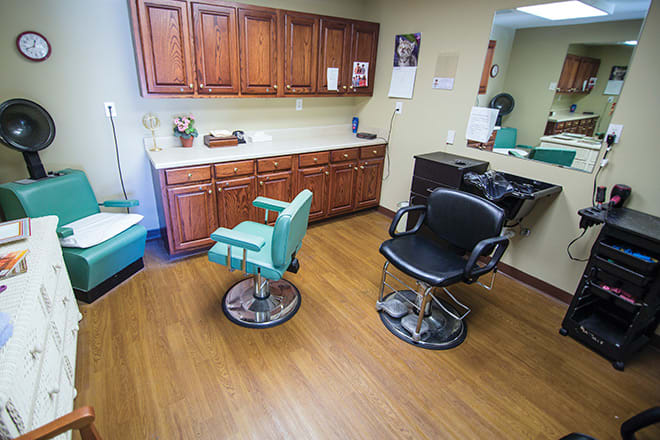 A well-organized hair salon with two styling chairs, cabinets, and a large mirror.