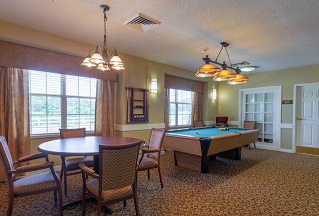A spacious game room featuring a billiards table and seating area.