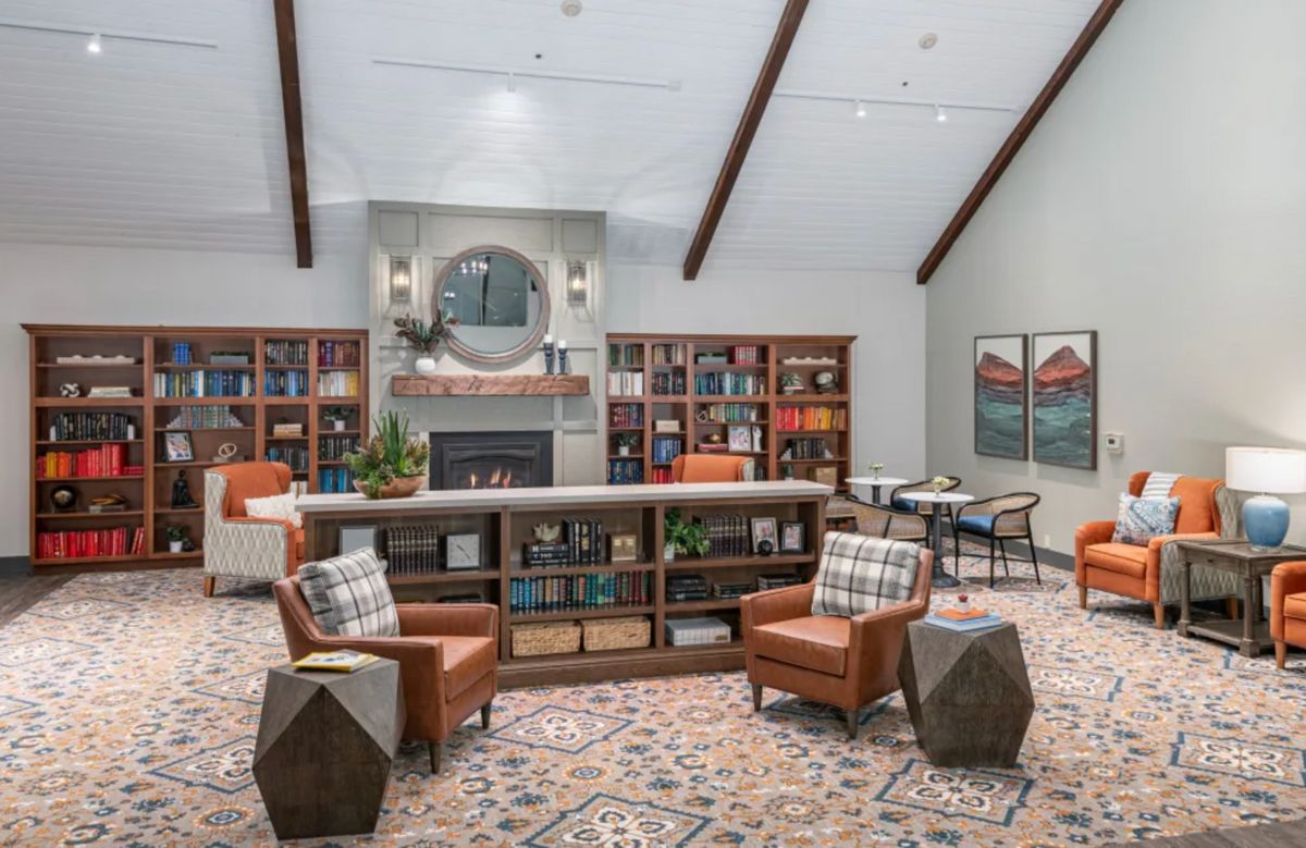 A cozy library interior with comfortable seating, bookshelves, and a fireplace.