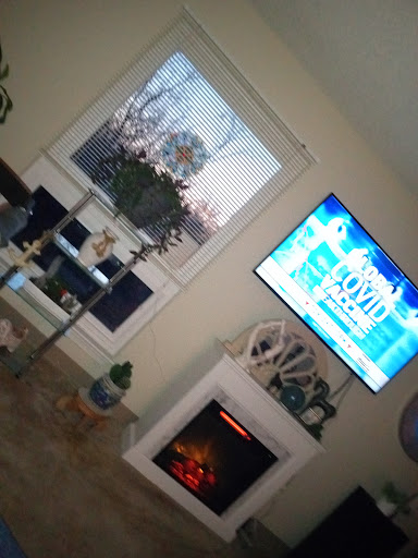 A cozy living room with a television displaying news and a warm fireplace.