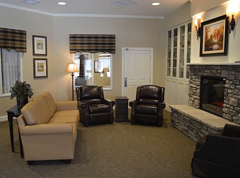 A cozy living room with a sofa, two armchairs, and a fireplace.